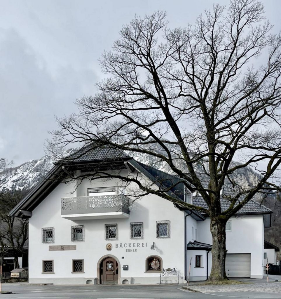 Außenansicht des Architekturprojekts der Ebner Bäckerei mit weißer Fassade, stahlgrauen Elementen und der Aufschrift "Bäckerei Ebner".